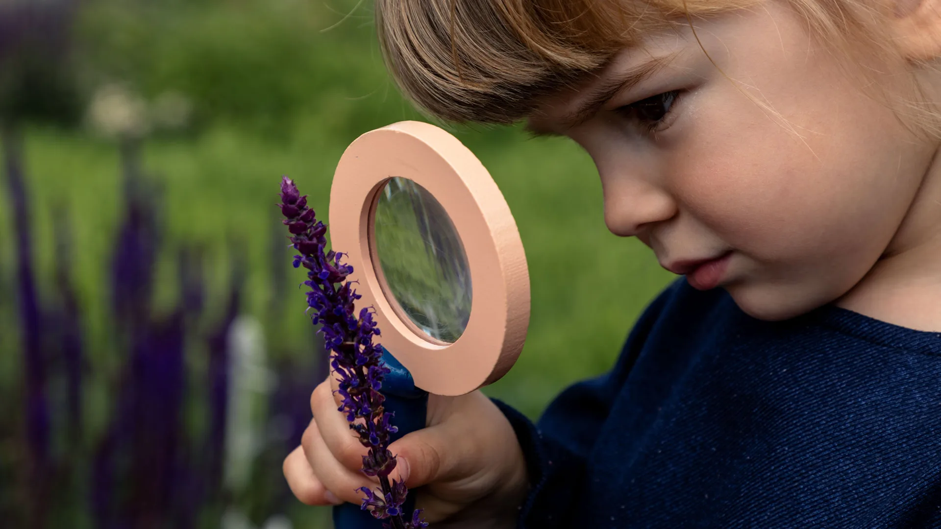 Bambina con lente d'ingrandimento nei Giardini